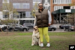 Suly Ortiz stands with her yellow Labrador retriever, Rubèn, at McCarren Park in the Brooklyn borough of New York, on Tuesday, April 26, 2022. (AP Photo/Emma H. Tobin)