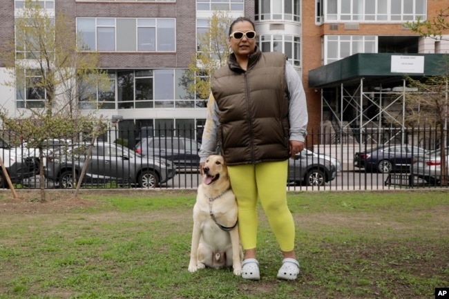 Suly Ortiz stands with her yellow Labrador retriever, Rubèn, at McCarren Park in the Brooklyn borough of New York, on Tuesday, April 26, 2022. (AP Photo/Emma H. Tobin)