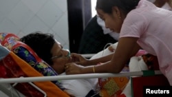 Naing Ngan Lynn, a candidate for National League for Democracy (NLD) party who was attacked on Thursday evening, lies on a hospital bed as his wife takes care of him in Yangon General hospital in Yangon, Myanmar, October 30, 2015.