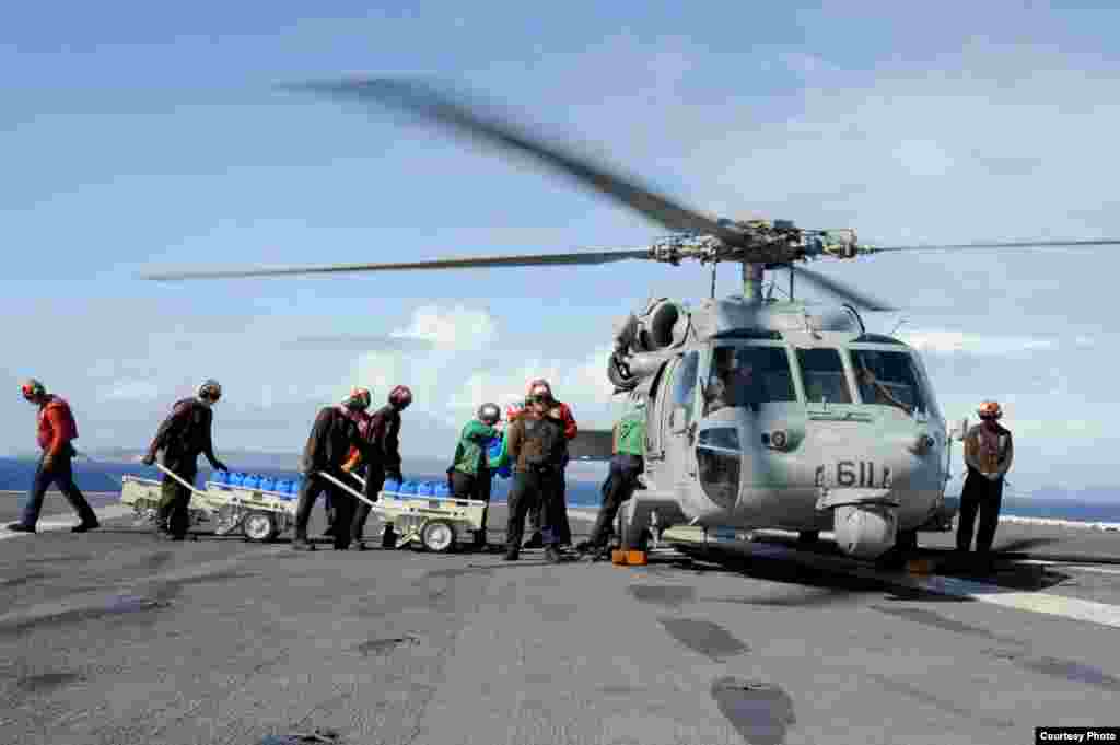 Sailors load fresh water onto an MH-60S Seahawk on the flight deck of the USS George Washington to be delivered ashore in support of Operation Damayan, Nov. 16, 2013. (U.S. Navy)