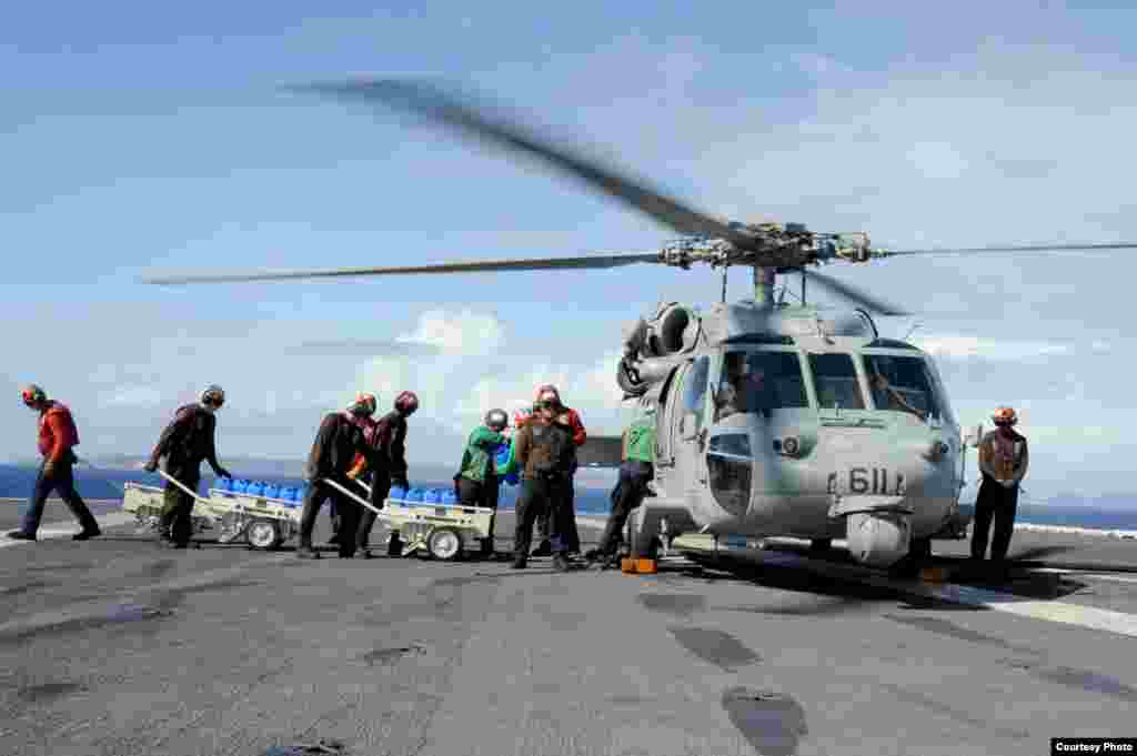 Sailors load fresh water onto an MH-60S Seahawk on the flight deck of the USS George Washington to be delivered ashore in support of Operation Damayan, Nov. 16, 2013. (U.S. Navy) 