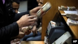 FILE - Egyptians count money at a currency exchange office in downtown Cairo, Jan. 2, 2013. 