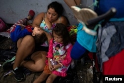 FILE - Tatiana, from El Salvador, sits with her children Michael Daniel, 3, and Maria Teresa, 5, amid a caravan of thousands of migrants from Central America taking a rest while en route to the United States, in Tapachula city center, Mexico, Oct. 21, 2018.