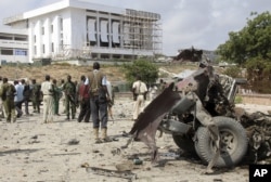FILE - Somali soldiers stand near the twisted car-bomb that exploded near Somali parliament’s headquarters, in Mogadishu, Somalia, November 7, 2012.