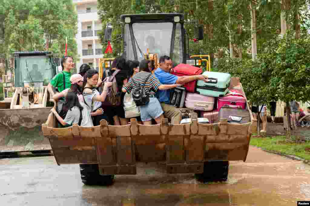 Students are transported by a forklift through a flooded area at a college in Guilin, Guangxi province, China, July 3, 2017.
