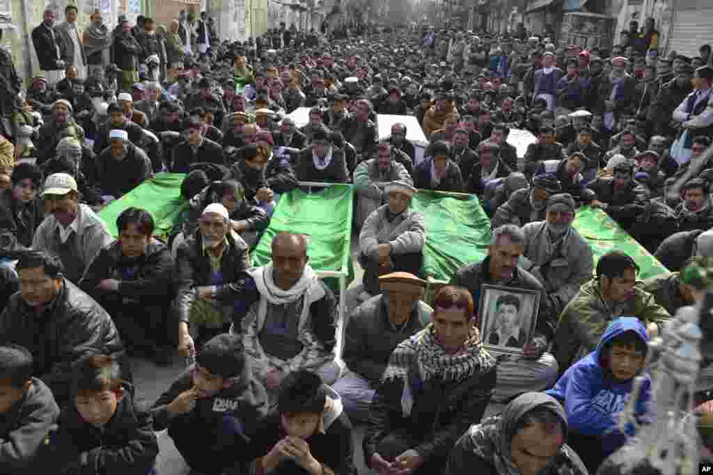 Relatives and mourners of Shi'ite pilgrims who were killed in a Tuesday bomb blast, protest sitting next to their bodies, in Quetta, Jan. 22, 2014.