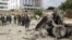 Somali soldiers stand near the twisted car-bomb that exploded near Somali parliament’s headquarters, in Mogadishu, Somalia, November 7, 2012.