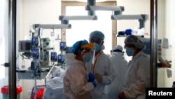 Medical workers talk before taking care of a patient infected with COVID-19 at the intensive care unit (ICU) of Ramon y Cajal hospital amid the coronavirus disease (COVID-19) outbreak in Madrid, Spain, Oct. 30, 2020. 