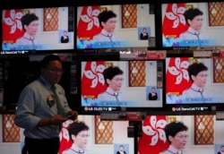 A shopper walks near televisions broadcasting Hong Kong Chief Executive Carrie Lam's speech in Hong Kong, Oct. 16, 2019.