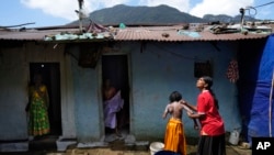 Muthuthewarkittan Manohari, a tea plantation worker, right, bathes her younger daughter Madubhashini, as her elder daughter Shalani, center, stands at the doorway of their small house in Spring Valley Estate in Badulla, Sri Lanka, Sept. 9, 2024.