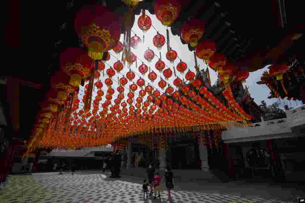 Turis berjalan di bawah lampion tradisional China yang dipajang menjelang perayaan Tahun Baru Imlek di sebuah kuil di Kuala Lumpur, Malaysia (10/1). (Foto: AP)