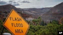 In this photo provided by Santa Barbara County Fire Department, a flash flood area sign is posted, as evacuations have been issued for several fire-ravaged communities in Santa Barbara, California, Jan. 8, 2018. 