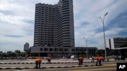 FILE - The Melia Cohiba hotel stands tall as workers repaint pavement markings along the Malecon in preparation for Pope Francis' visit in Havana, Cuba. President Trump is preparing to tighten the six-decade trade embargo on Cuba on Monday, March 4, 2019.