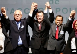 FILE – From left, Mohammed Chouaib, head of delegation from the U.N.-recognized government in the eastern city of Tobruk, Libya; Fayez Sarraj, Libyan prime minister; and Dr. Saleh Almkhozom, second deputy chairman of the Libyan General National Congress, react after signing a U.N.-sponsored deal aiming to end Libya's conflict in Sikhrat, Morocco, Dec. 17, 2015.