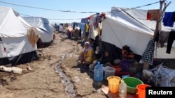 FILE - Displaced families, who fled from Islamic State violence in Mosul, sit at a refugee camp in Iraq, Oct. 22, 2014.