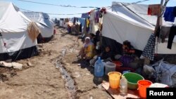 FILE - Displaced families, who fled from Islamic State violence in Mosul, sit at the Ali Awa refugee camp near Khanaqin city, Iraq, Oct. 22, 2014.