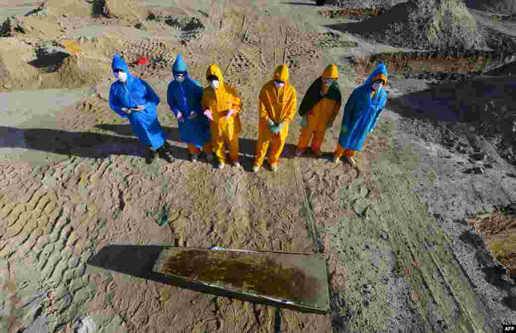 Iraqi volunteers in full hazmat gear pray over the coffin of a 50-year-old victim of the COVID-19 virus before her burrial at a cemetary specifically opened for such deaths, 20 kms from the central holy city of Najaf.