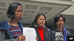 United Filipinos in Hong Kong chairperson Dolores Balladares, Asian Migrants' Coordinating Body spokesperson Eni Lestari and Association of Indonesian Migrant Workers' representative Ganika Diristiani (from L-R), pose with the court verdict outside the Hi