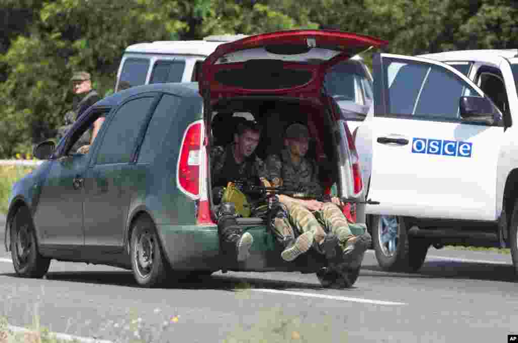 Pro-Russian rebels travel past a convoy of the OSCE mission in Ukraine outside the city of Donetsk, eastern Ukraine, July 30, 2014.