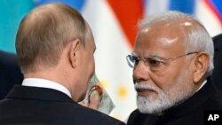 O Presidente russo, Vladimir Putin, e o Primeiro-Ministro indiano, Narendra Modi, interagem no final da reunião de formato alargado da cimeira dos BRICS em Kazan, Rússia, quarta-feira, 23 de outubro de 2024.