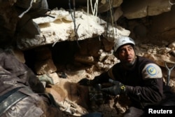 Civil Defense members look for survivors under rubble of damaged buildings after airstrikes on the northern neighborhood of Idlib city, Syria, Dec. 5, 2016.