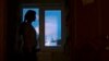 ARHIVA - Žena koju je tukao suprug gleda kroz prozor sigurne kuće za žene žrtve porodičnog nasilja (Foto: AP/Pavel Golovkin)