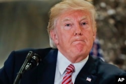 FILE - President Donald Trump pauses as he answers questions in the lobby of Trump Tower in New York, Aug. 15, 2017.