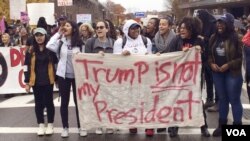 اعتراض کنندگان شعارهای "ترمپ رئیس جمهوری ما نیست" را حمل می کنند