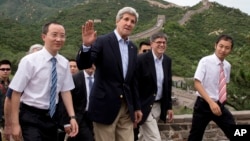 U.S. Secretary of State John Kerry, center, and U.S. Treasury Secretary Jacob Lew, second from right, wave to journalists as they visit to Badaling Great Wall of China in Beijing, China, July 8, 2014. 