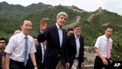 U.S. Secretary of State John Kerry, center, and U.S. Treasury Secretary Jacob Lew, second from right, wave to journalists as they visit to Badaling Great Wall of China in Beijing, China, July 8, 2014. 