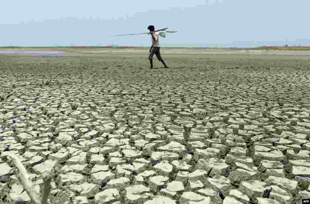 An Indian man walks over the parched bed of a reservoir on the outskirts of Chennai.