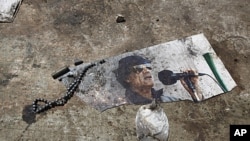 A picture of ousted Libyan leader Muammar Gadhafi is seen on the ground of the ransacked Bab al-Aziziya compound in Tripoli, August 26, 2011