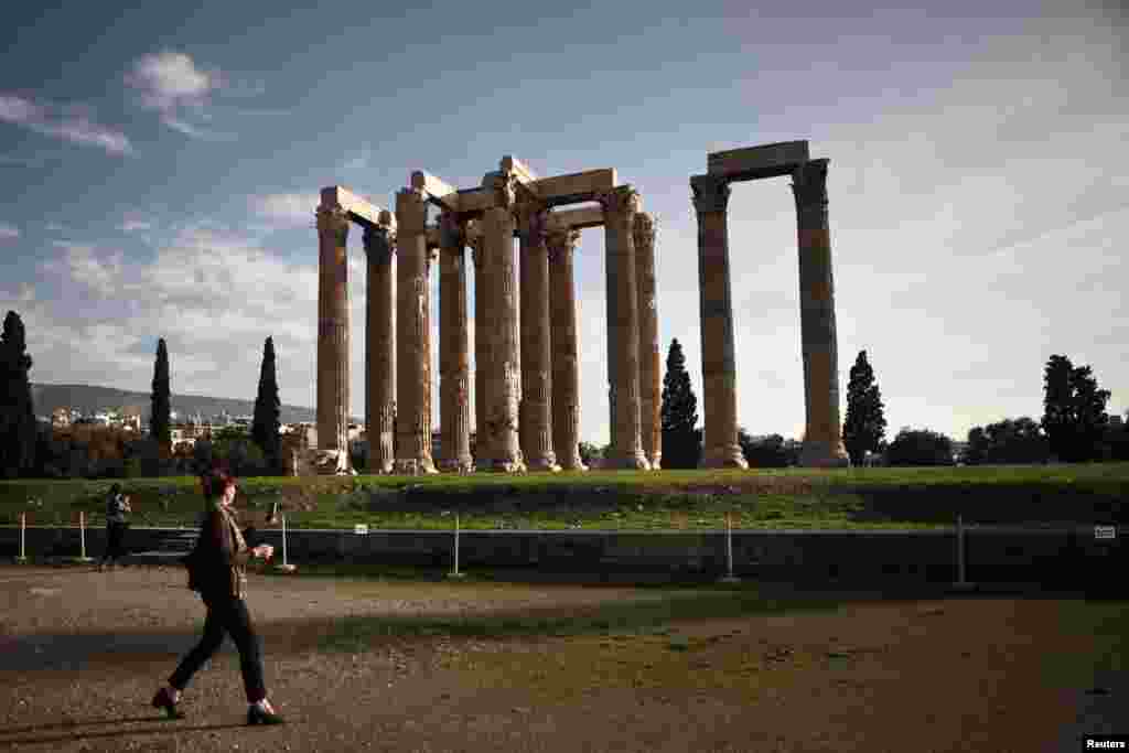 A tourist walks at the archaeological site of the Temple of the Olympian Zeus in Athens, Greece.