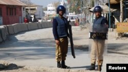 FILE - Policemen guard near the central prison where a court convicted 31 people over the campus lynching of a university student last year who was falsely accused of blasphemy, in Haripur, Pakistan, Feb. 7, 2018.
