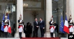 Outgoing French President Francois Hollande, center left, welcomes incoming French President Emmanuel Macron as he arrives for his inauguration ceremony at the Elysee palace in Paris, May 14, 2017.