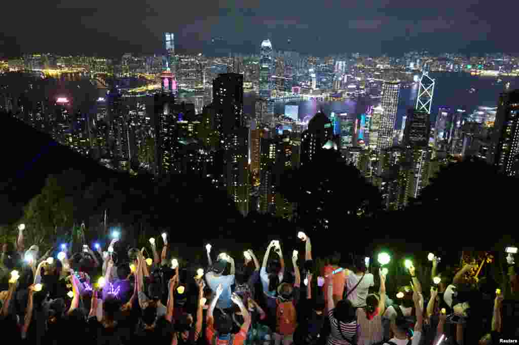 Anti-extradition bill protesters hold up hands and lights during a demonstration to call for political reforms in Hong Kong, China.