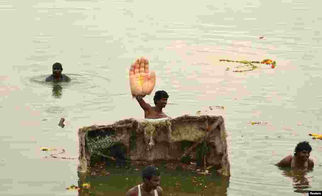 Seorang pria India memegang tangan patung Dewa Ganesha, dewa kemakmuran, selama upacara perendaman patung dalam festival Ganesh Chaturthi di kota Hyderabad, India selatan.