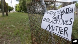 A sign calling for justice is attached to a fence near the site where Walter Scott was killed in North Charleston, S.C., Wednesday, April 8, 2015.