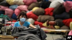 FILE - A volunteer sews blankets made from recycled plastic bottles at The Tzu Chi Foundation factory in Taipei, Taiwan. Taiwanese exports are falling, driving the island's economy into recession.