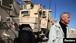 FILE - U.S. Secretary of Defense Chuck Hagel stands next to MRAP vehicles after speaking to U.S. troops at Camp Bastion, Afghanistan, Dec. 8, 2013. 