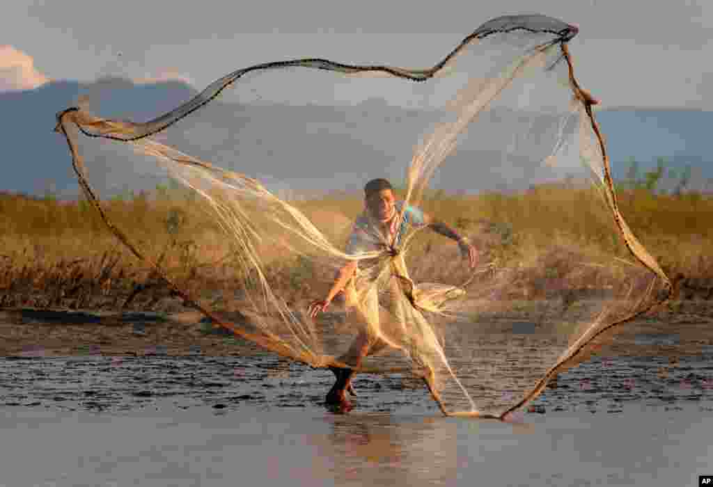 August 30: An Indian villager throws a fishing net into the River Brahmaputra at Suwalkuchi, India. (AP Photo/ Anupam Nath)