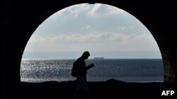 FILE - A man walks along the sea front in Swansea on October 13, 2015.