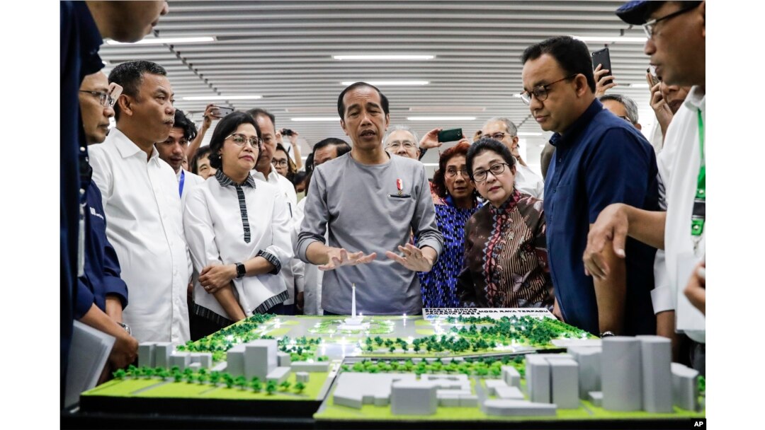 Presiden Joko “Jokowi” Widodo (tengah) mengamati model jalur Moda Raya Terpadu dalam peresmian di Jakarta, 24 Maret 2019.