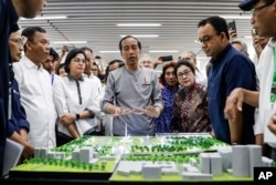 Presiden Joko “Jokowi” Widodo (tengah) mengamati model jalur Moda Raya Terpadu dalam peresmian di Jakarta, 24 Maret 2019.