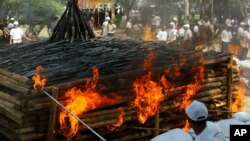 Cambodian officials inflame a pile of old guns collected nationwide during a weapon burning ceremony led by the government, in Kandal province, about 15 kilometers (9 miles), south of the capital Phnom Penh, Cambodia, Tuesday, June 20, 2006. (AP Photos/Heng Sinith)