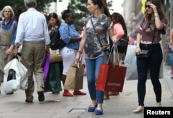 FILE - Shoppers carry bags in London, Britain, Aug. 25, 2016. The falling value of the British pound vs. other currencies is making London more attractive to bargain-hunters.