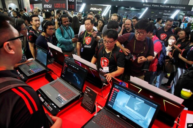 FILE - Visitors review computer products during Computex 2018, in Taipei, Taiwan, June 5, 2018.