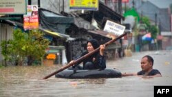 Seorang perempuan menggunakan rakit dari ban mengarungi banjir setelah hujan deras menyebabkan banjir di Bekasi, Jawa Barat, 1 Januari 2020. (Foto: AFP)