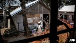 Health workers are seen through a bullet hole left in the window of an Ebola treatment center, which was attacked in early on March 9, 2019, in Butembo, Democratic Republic of the Congo.