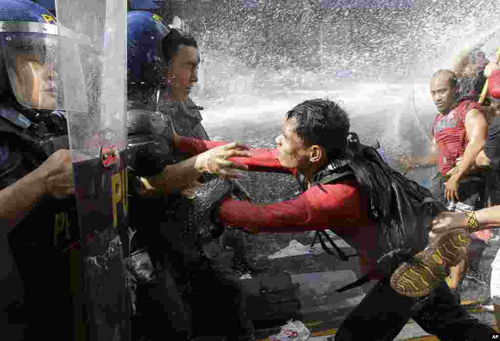 A protester pushes a policeman as they are dispersed while trying to get near the U.S. Embassy in Manila, Philippines, to protest against the visit of U.S. President Donald Trump.